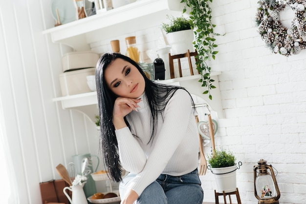 La bella ragazza fa colazione e beve il caffè in cucina. Stile di vita.