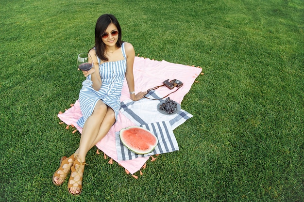 La bella ragazza gode del vino su un picnic.