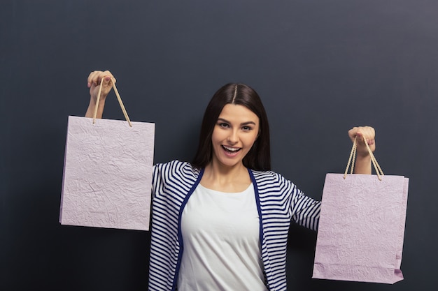 La bella ragazza in abbigliamento casual sta tenendo i sacchetti della spesa.