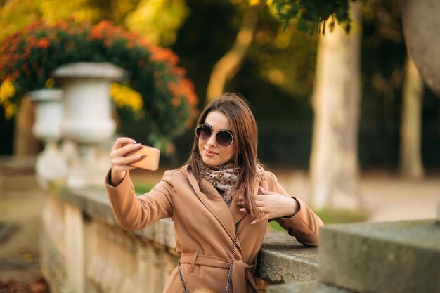 La bella ragazza in occhiali da sole fa foto sul selfie dello smartphone