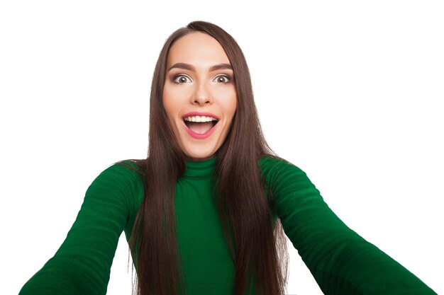 La bella ragazza in un dolcevita verde fotografa selfie