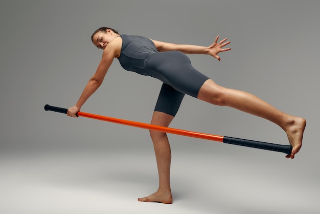 La bella ragazza in uniforme sportiva sta allenando il kung fu nell'atleta del combattente dello studio che pratica le arti marziali con un bastone