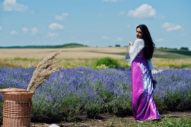 La bella ragazza indiana indossa l'abito tradizionale saree india nel campo di lavanda viola con cesto.