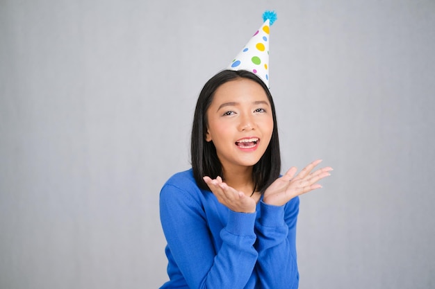 La bella ragazza indossa un maglione blu e un cappello da festa su backgroynd bianco