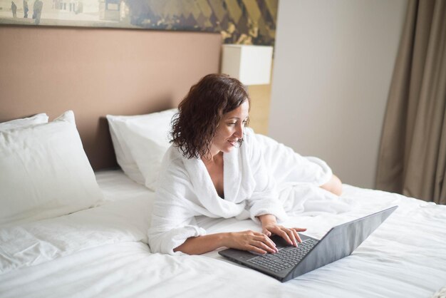 La bella ragazza lavora con un computer portatile in una stanza d'albergo durante il viaggio