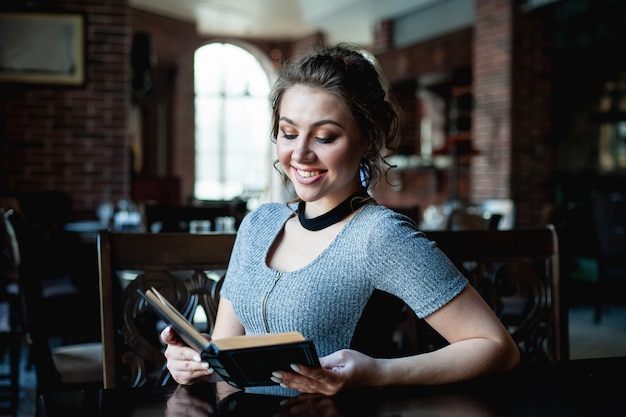 la bella ragazza legge un libro interessante in un caffè