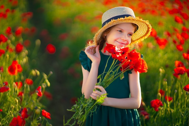 La bella ragazza nel campo del papavero gode della bellezza e degli aromi