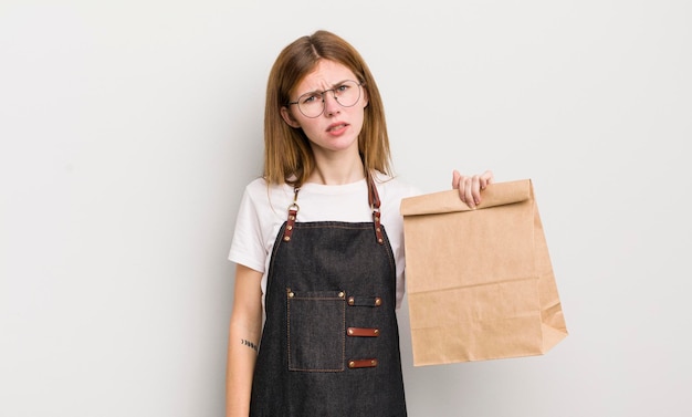 La bella ragazza rossa che si sente perplessa e confusa porta via il dipendente