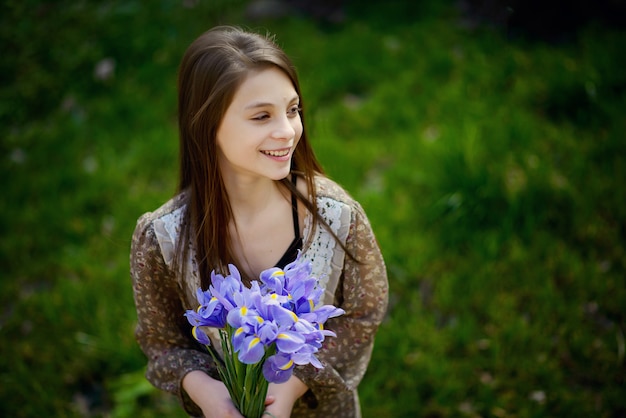 La bella ragazza si rallegra e sorride con un mazzo di fiori primaverili nelle sue mani. Focalizzazione morbida.