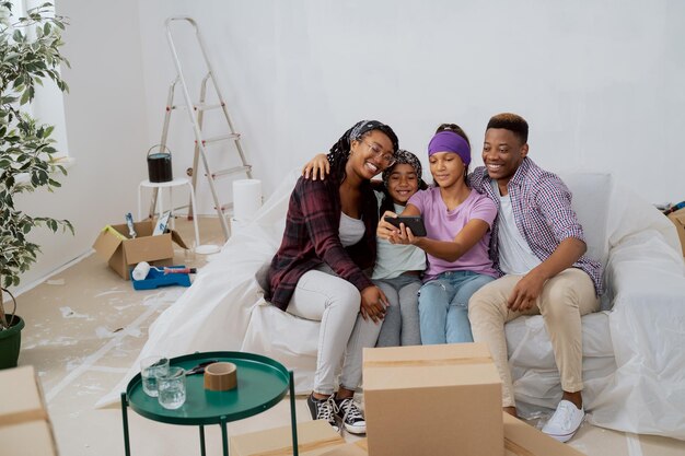 La bella ragazza si siede sul divano con la famiglia in un appartamento ristrutturato si fa un selfie con i genitori