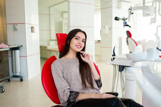 La bella ragazza sorride nella sedia dentale.