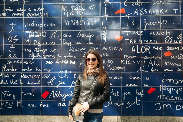 La bella ragazza sta camminando a Parigi vicino al muro della basilica tje dell'amore