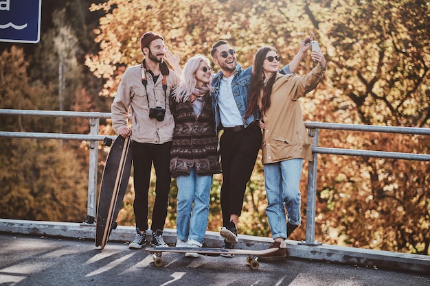 La bella ragazza sta facendo una foto di se stessa e dei suoi amici al parco autunnale.