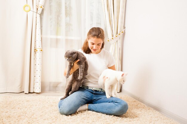 La bella ragazza sta giocando con i suoi gatti