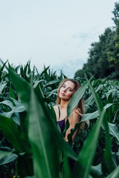 La bella ragazza sta nel campo di giovane cereale. Agricoltura.