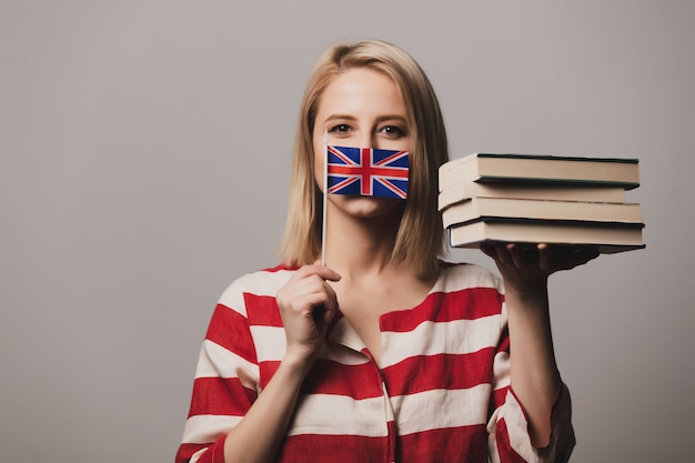 La bella ragazza tiene la bandiera e i libri britannici