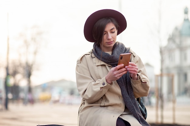 La bella ragazza usa uno smartphone all'aperto