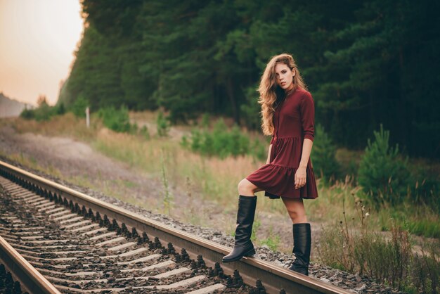 La bella ragazza vaga con capelli naturali ricci gode della natura in foresta sulla ferrovia.