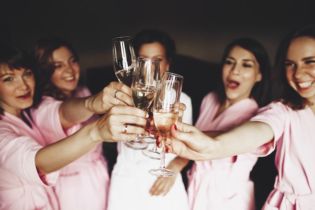 La bella sposa e le ridenti damigelle in abiti rosa tintinnavano gli occhiali con lo champagne