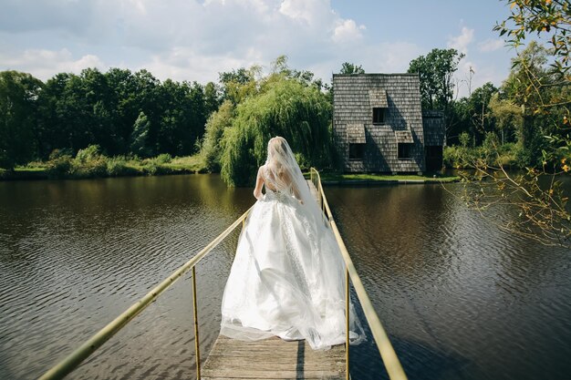 La bella sposa sta camminando sul ponte Foto di nozze all'aperto