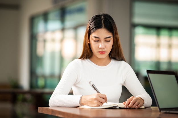 La bella studentessa asiatica si siede per l'esame agli studenti dell'aula universitaria che si siedono nel college universitario di stile di vita di istruzione di fila