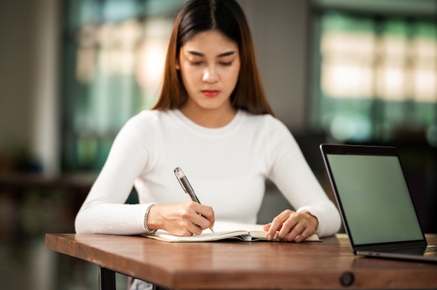 La bella studentessa asiatica si siede per l'esame agli studenti dell'aula universitaria che si siedono nel college universitario di stile di vita di istruzione di fila