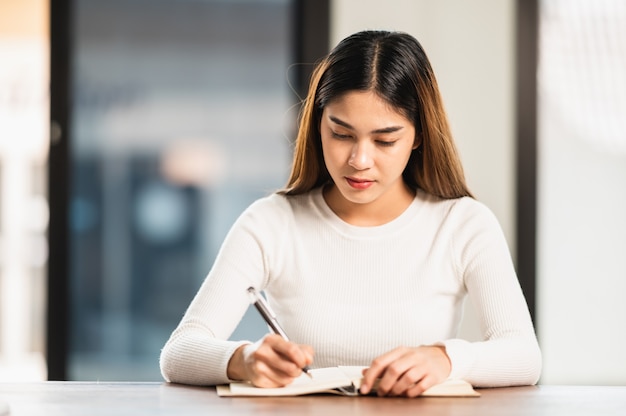 La bella studentessa asiatica si siede per l'esame agli studenti dell'aula universitaria che si siedono nel college universitario di stile di vita di istruzione di fila