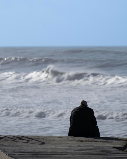 La bellezza della solitudine in riva al mare Una persona anziana sola che contempla l'azzurro infinito