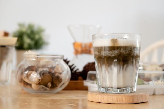 La bevanda giapponese del tè verde hojicha è un latte in un bicchiere posto su un vassoio di legno.
