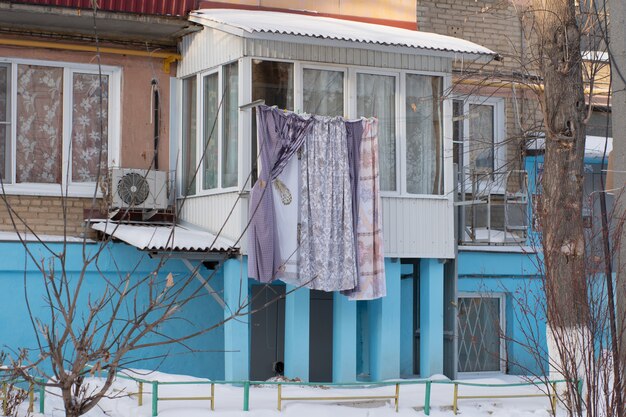 La biancheria si asciuga in inverno su una corda per strada, una casa blu, cespugli.