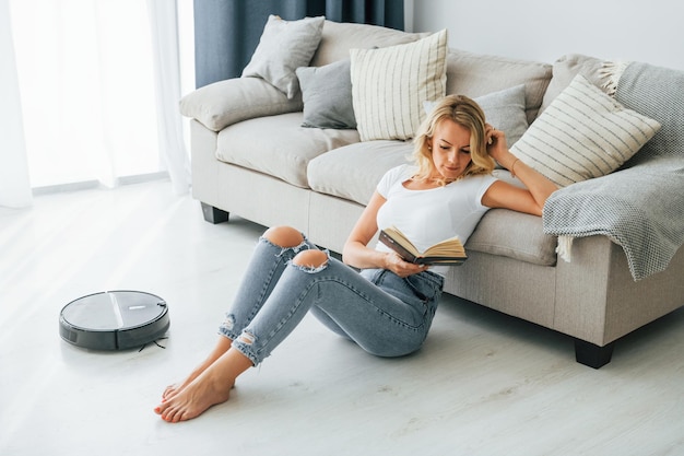 La bionda si siede sul pavimento La donna in abiti casual è in casa a casa