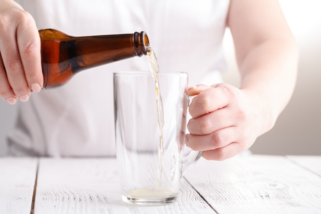 La birra di versamento femminile in tazza di vetro, si rilassa il concetto