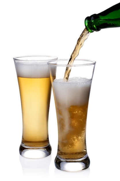 La birra viene versata su un bicchiere su uno sfondo bianco