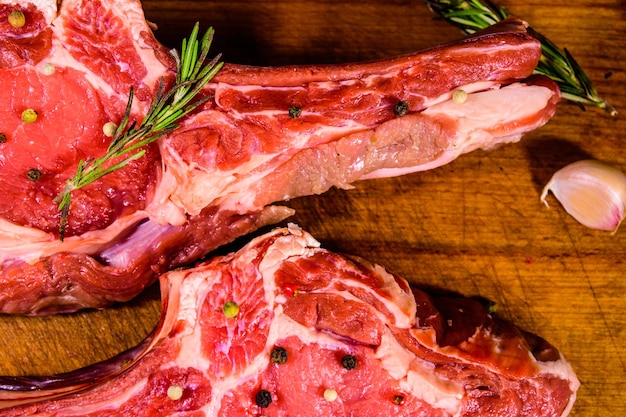 La bistecca di ribeye cruda spezia il rosmarino e l'aglio sul tagliere di legno Vista dall'alto