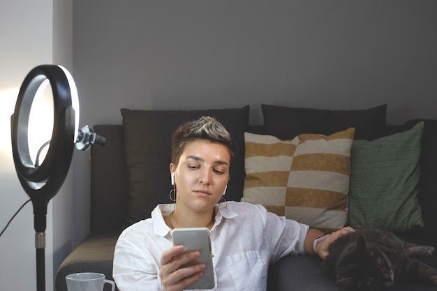 La blogger donna sta usando lo smartphone a casa l'illuminazione dello studio per lo stile di vita millenario del blogger
