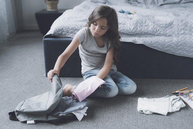 La borsa d&#39;imballaggio sveglia della ragazza si siede sul pavimento in camera da letto