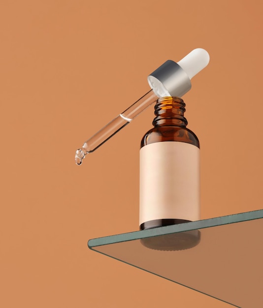 la bottiglia con il liquido trasparente è posizionata su uno scaffale di vetro lo sfondo arancione contrasta