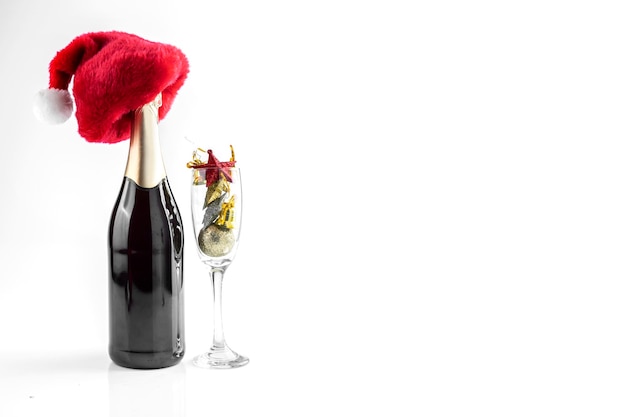 La bottiglia di champagne con cappello da Babbo Natale e bicchiere di champagne con decorazioni natalizie