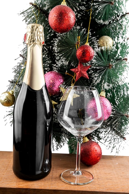 La bottiglia di champagne e il bicchiere di vino con l'albero di Natale