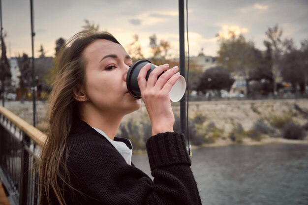 La bruna beve una bevanda calda da una tazza di carta