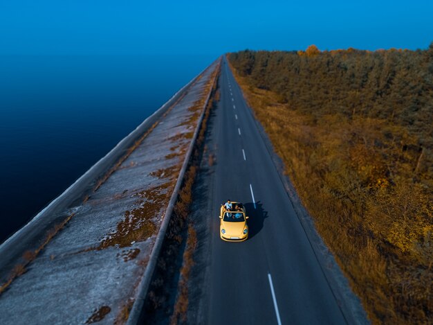 La cabriolet gialla che guida sulla strada costiera