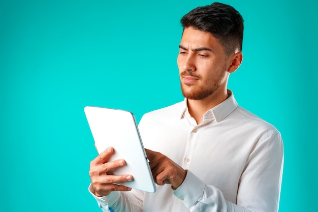 La camicia bianca da portare del giovane uomo d'affari tiene la compressa digitale