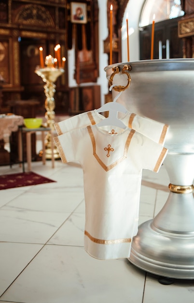 La camicia da battesimo è appesa a una gruccia sullo stabilimento balneare della Chiesa. Il battesimo di un bambino.