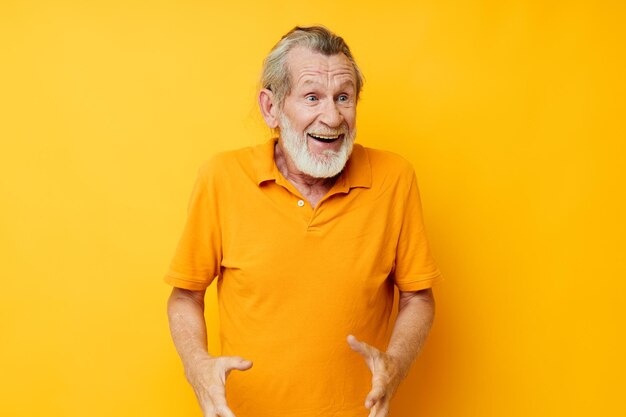 La camicia gialla dell'uomo dai capelli grigi senior che posa le emozioni ha isolato lo sfondo