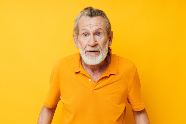 La camicia gialla dell'uomo dai capelli grigi senior che posa le emozioni ha isolato lo sfondo