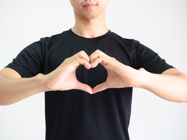 La camicia nera dell'uomo del ritratto fa il cuore con le mani ritaglia il corpo su sfondo bianco isolato