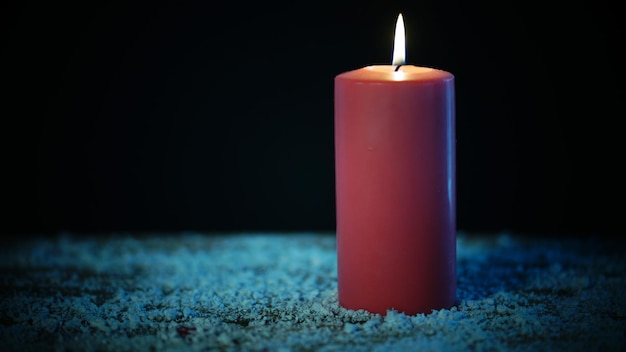 La candela rossa di Natale si illumina in uno sfondo scuro