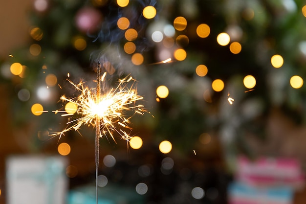 La candela scintillante delle stelle filanti di Natale brucia nella decorazione dell'illuminazione di natale del fondo dell'albero di natale a