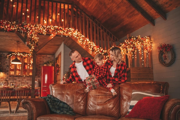 La candida autentica famiglia felice in pigiama scozzese rosso trascorre del tempo insieme al lodge decorato per Natale