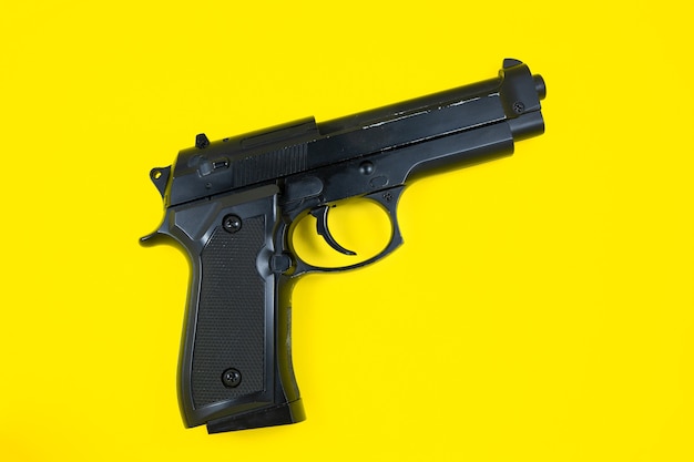 La canna di una pistola nera, la pistola si trova su uno sfondo giallo. Avvicinamento.